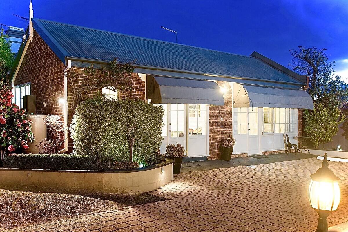 A brick building with a metal roof, a covered patio area, and a well-lit entrance.