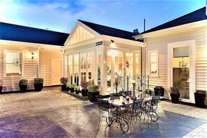 Eine überdachte Terrasse mit Glasveranda, Sitzgelegenheiten im Freien und Blumentöpfen.