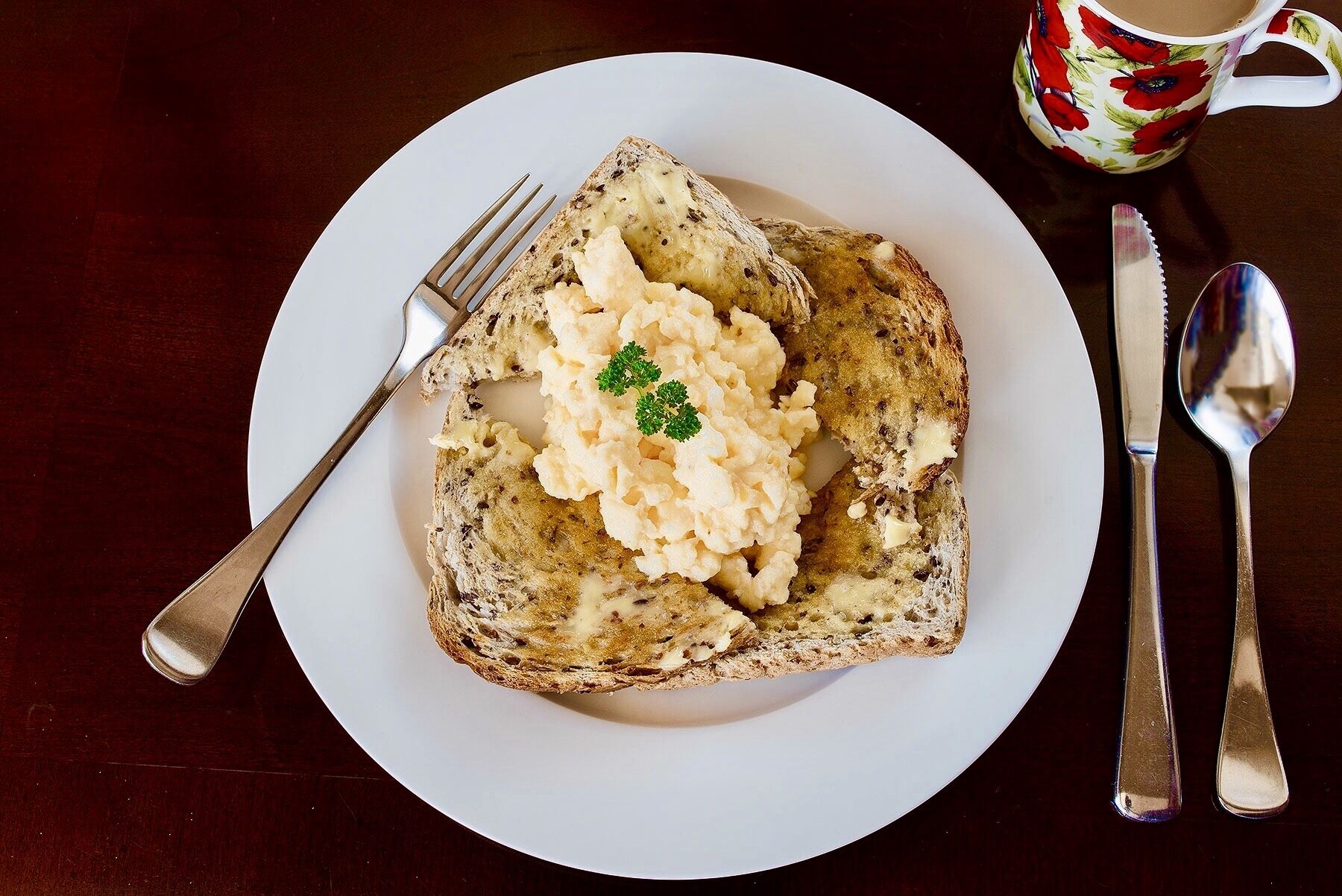 A plate with toast and mashed potatoes, a fork, a knife, and a spoon on a table.