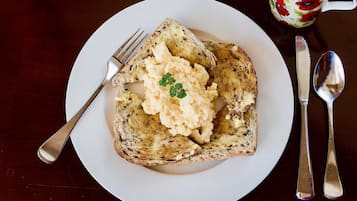 A plate with toast and mashed potatoes, a fork, a knife, and a spoon on a table.