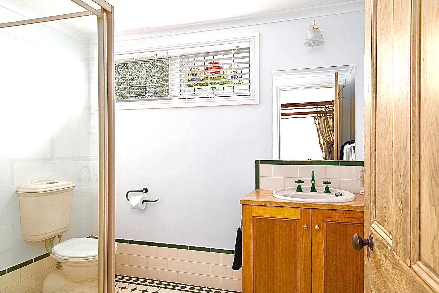 Een badkamer met toilet, wastafel met spiegel en douchehoek.