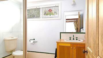Een badkamer met toilet, wastafel met spiegel en douchehoek.