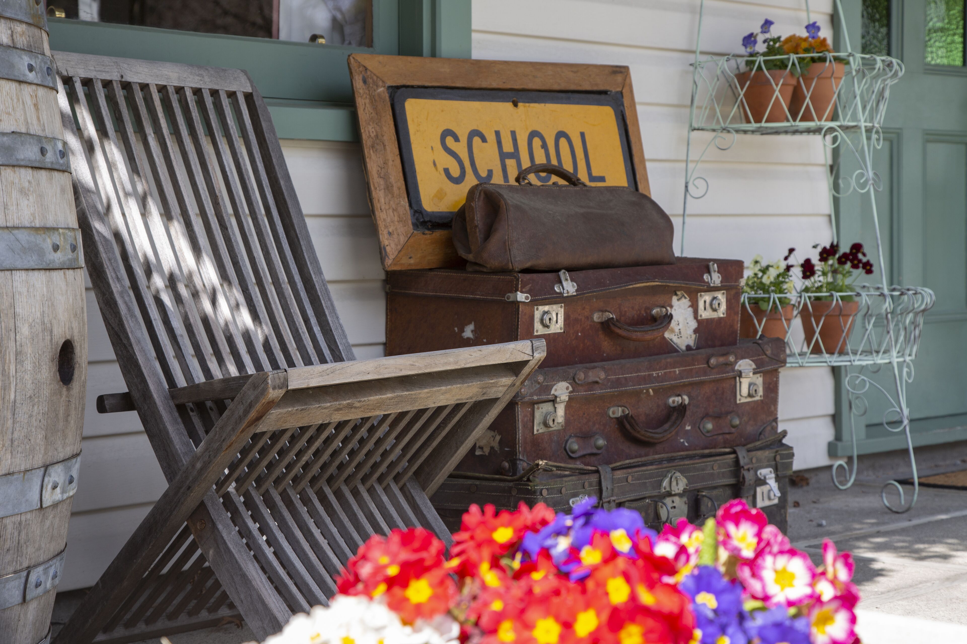 A wooden bench, a suitcase, and a sign that reads "SCHOOL" on a building facade.
