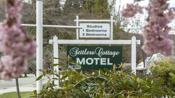 Señal para el motel Settlers Cottage, con un poste blanco y un cartel verde.
