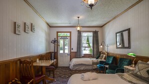 Habitación de hotel con dos camas, un escritorio, sillas, una lámpara y un espejo.