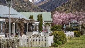 Un motel con cerca viva blanca, techo verde y un letrero que indica que está decorado con encanto de la vieja Europa.