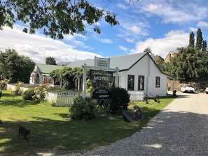 A white building with a sign indicating it is a motel with 2 bedrooms. - Settlers Cottage Motel (Arrowtown)