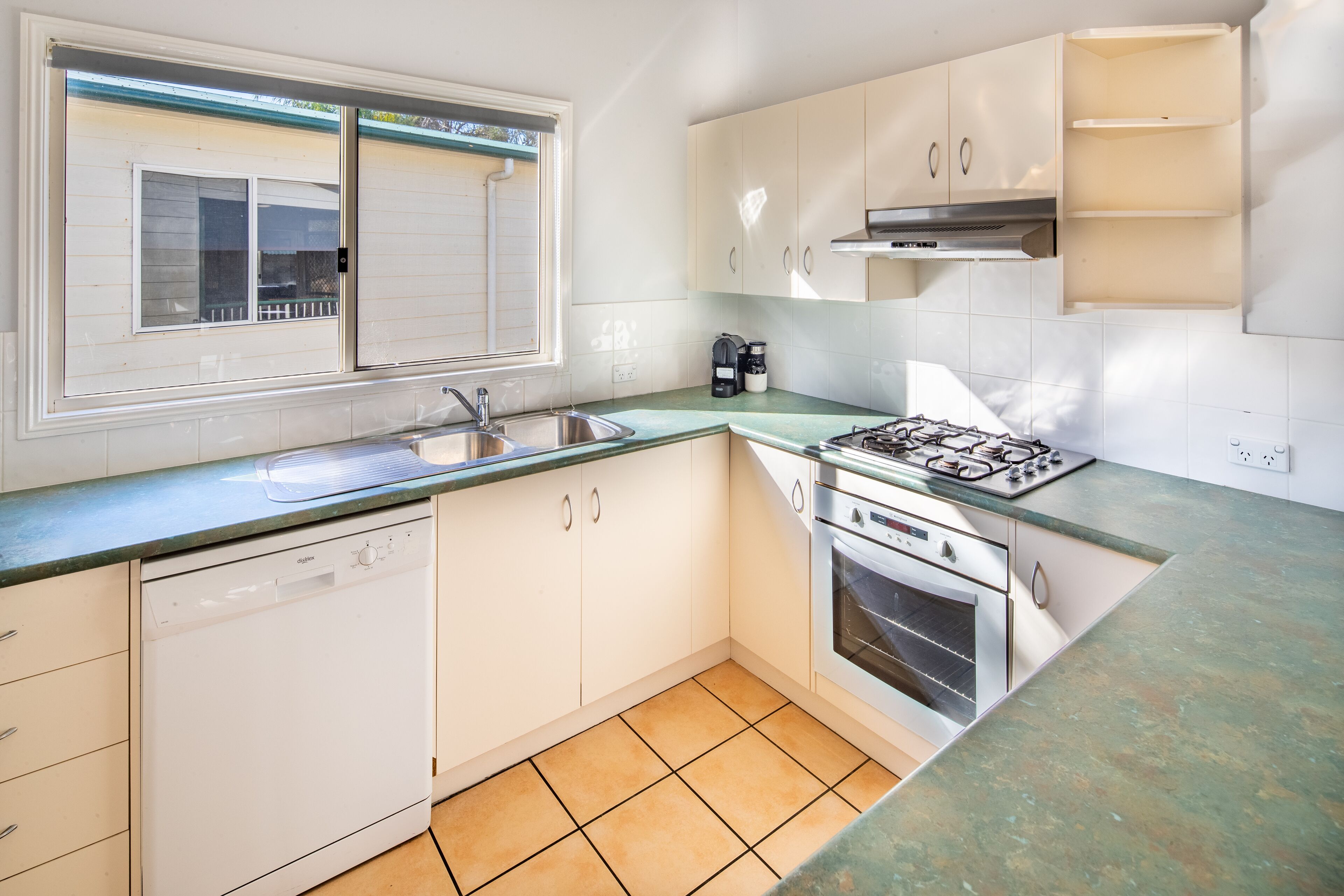 A kitchen with a dishwasher, sink, stove, and cabinets.