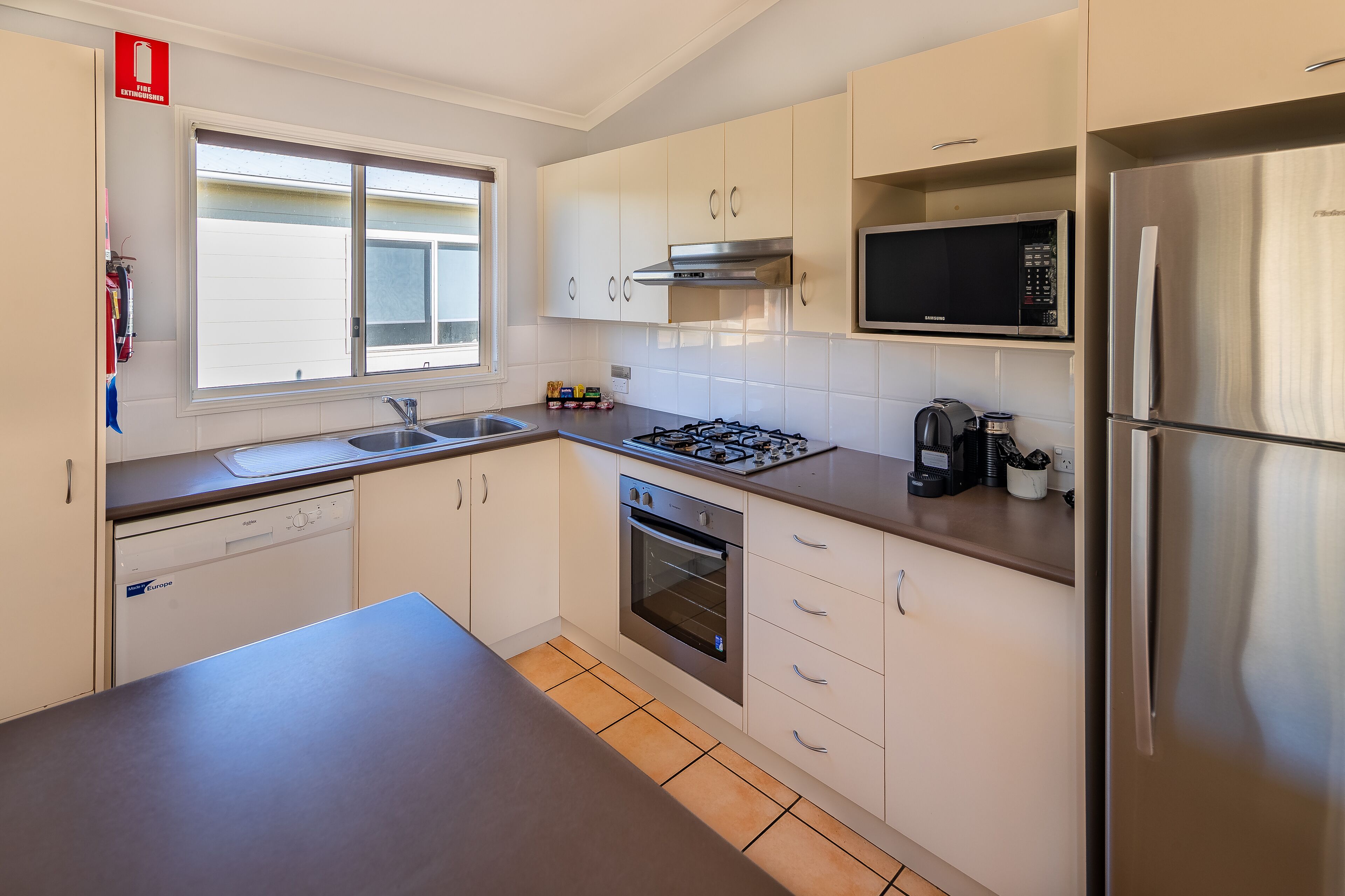 A modern kitchen with white cabinets, a stainless steel refrigerator, a microwave, a gas stove, and a dishwasher.