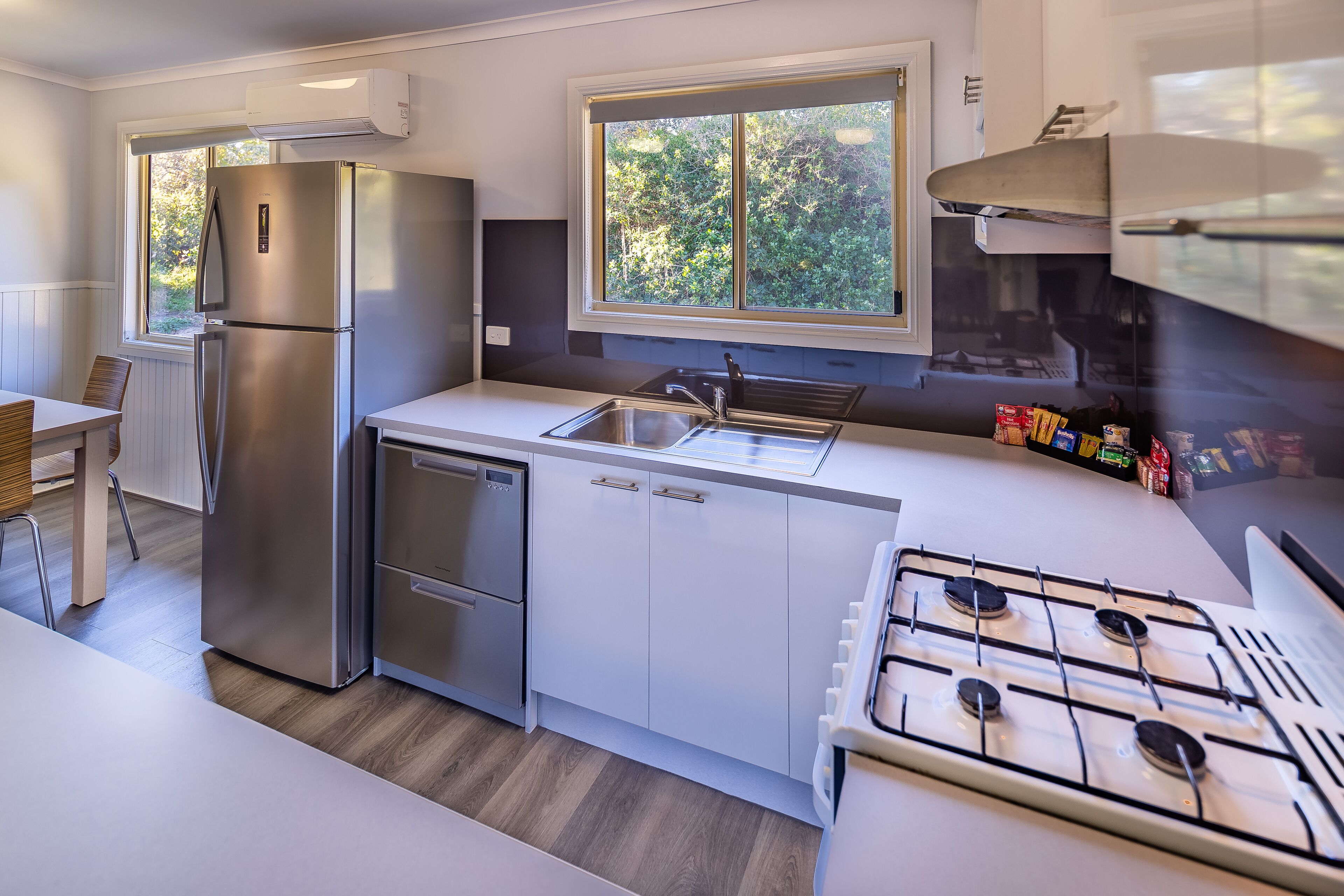 A modern kitchen with a stainless steel refrigerator, a gas stove, and a window providing natural light.