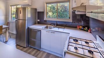 A modern kitchen with a stainless steel refrigerator, a gas stove, and a window providing natural light.