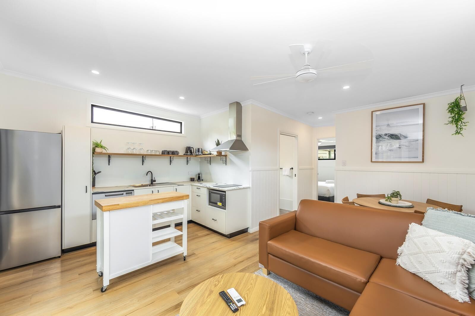 A modern apartment with a kitchenette, a sofa, and a dining area.