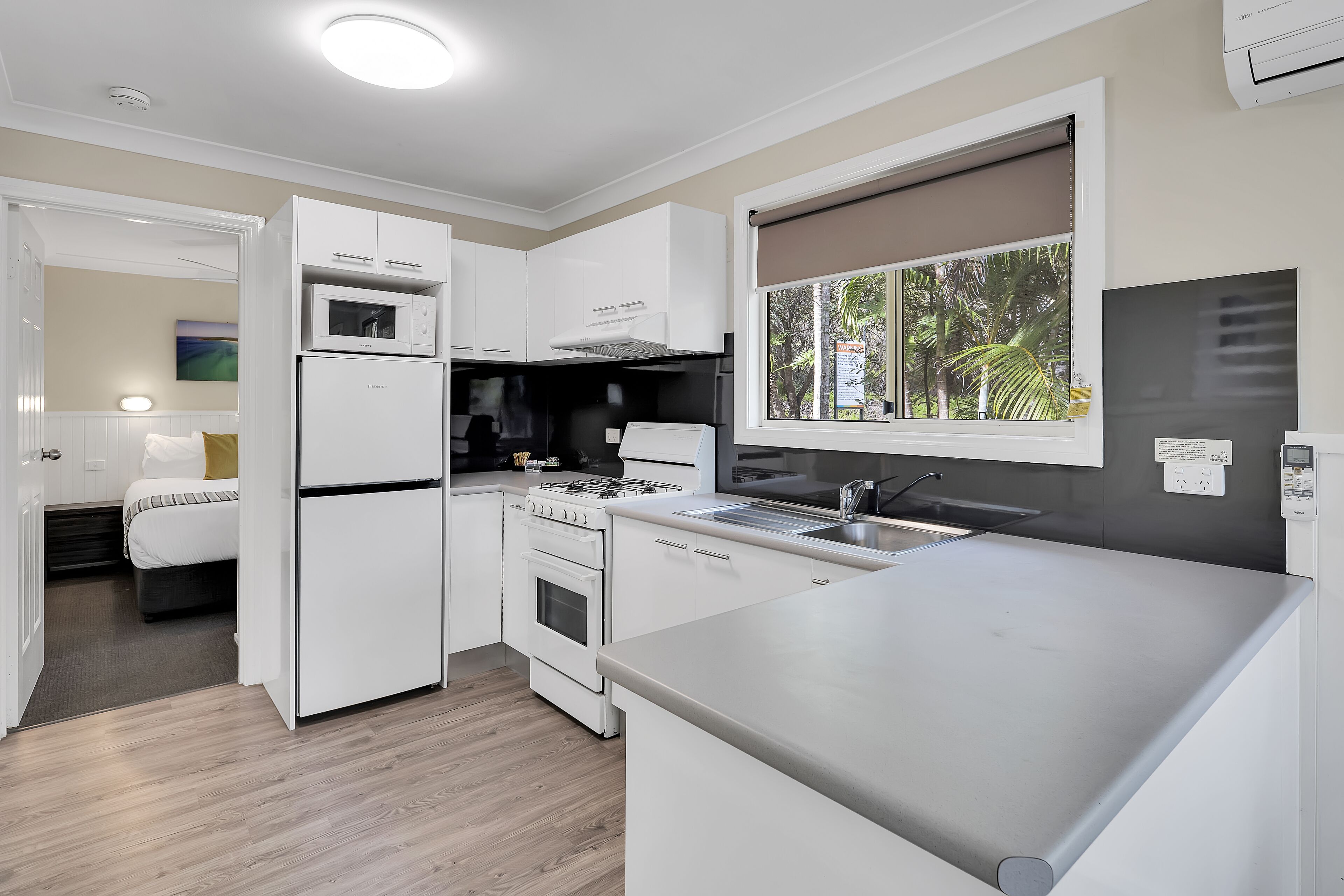 A modern kitchen with white cabinetry, a built-in oven, microwave, and a large countertop.