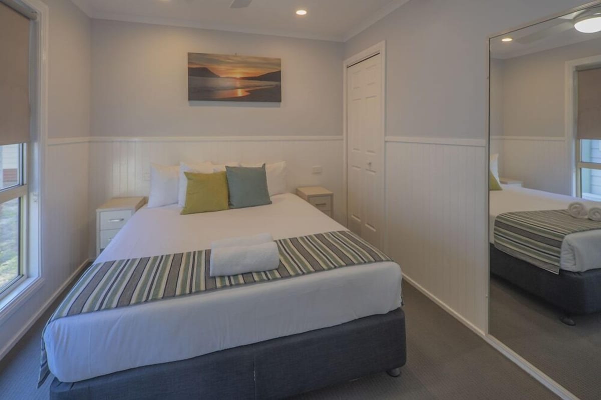 A bedroom with a bed, nightstand, and a mirror.