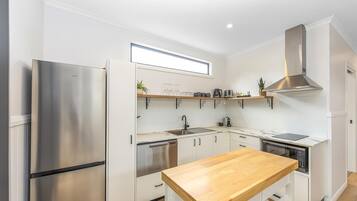 Una cocina moderna con armarios blancos, electrodomésticos de acero inoxidable y encimera de madera.