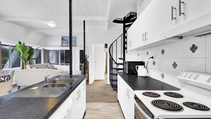 Una cocina moderna con armarios blancos, encimera negra y estufa blanca.