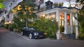 Ein modernes Hotel mit einem geparkten Auto davor, umgeben von üppiger Vegetation und einem gut beleuchteten Eingang.