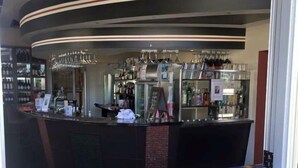 A bar area with a curved counter, shelves with bottles, and hanging glasses. - The Astra Hotel (Broken Hill)