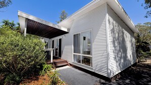 Une maison moderne dotée d’un porche abrité, de grandes fenêtres et d’un toit en pente.