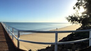 A wooden boardwalk leading to a beach with a white railing. - Sunseeker Motel (Scarness)