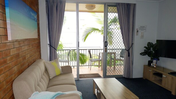 A living room with a sofa, a wooden coffee table, and a TV on a wooden cabinet. - Sunseeker Motel (Scarness)