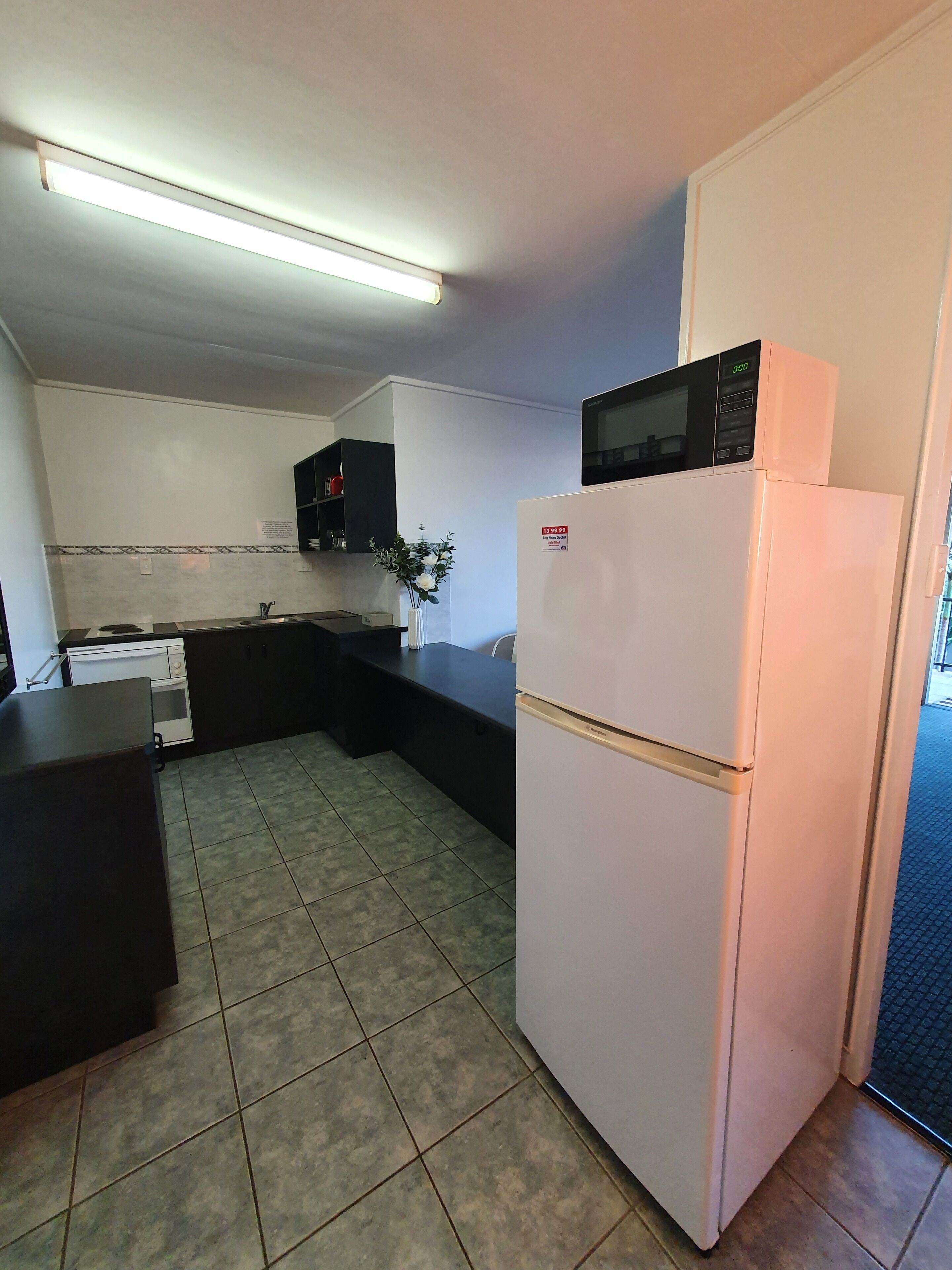 Una cocina compacta con un refrigerador blanco, un microondas y una estufa.