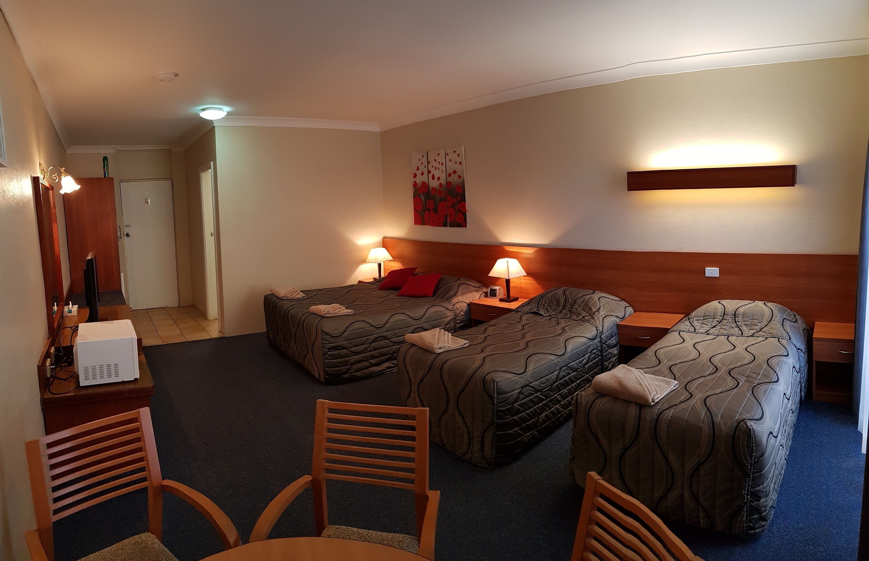 A hotel room with two single beds, a desk with a computer, a chair, and a small table.