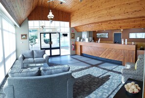A spacious lobby with a wooden ceiling, a reception desk, grey sofas, and a patterned rug. - Amber Court Motel, Coonabarabran (Coonabarabran)