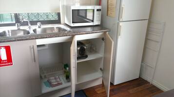 Una cocina compacta con microondas, pileta y un cartel de extintor.