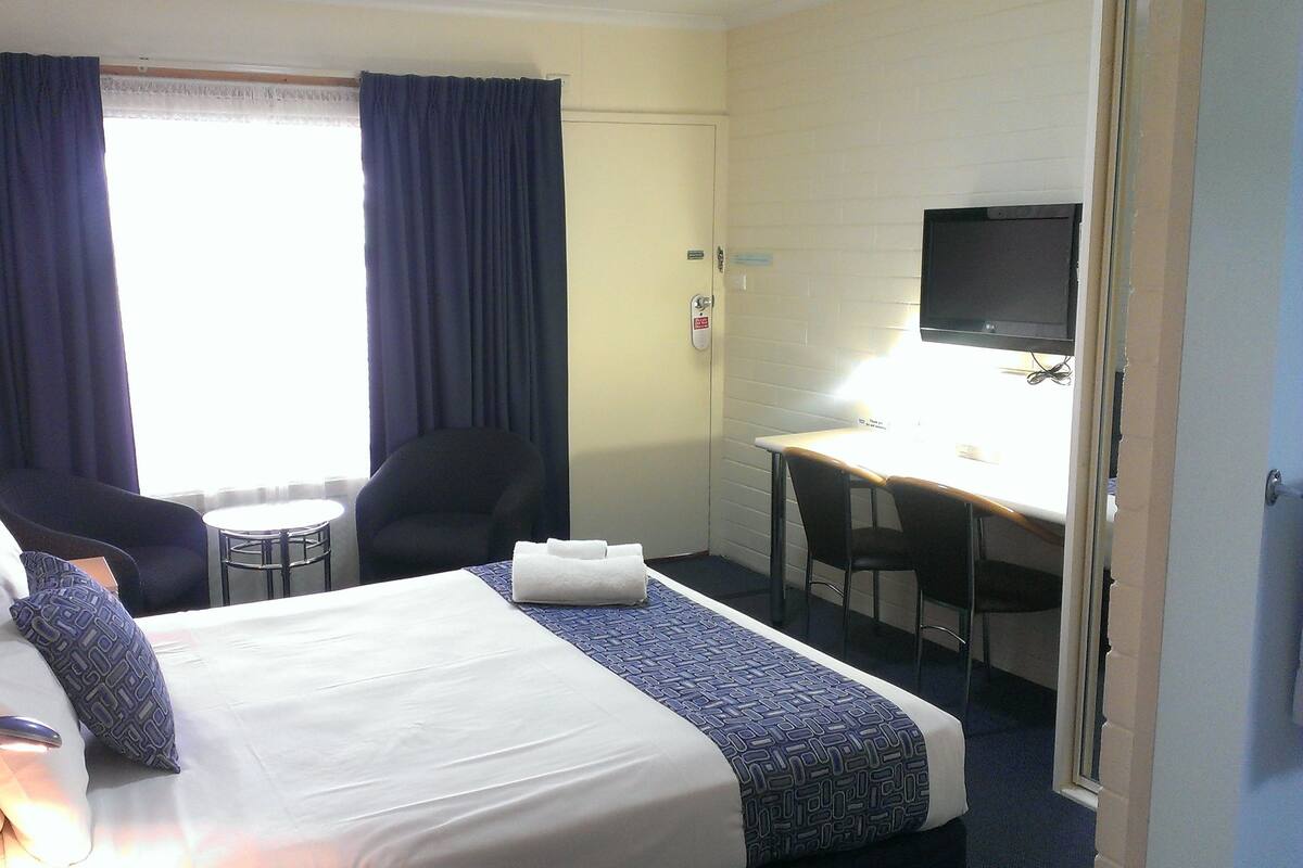 Ein Hotelzimmer mit Bett, Schreibtisch, Stuhl und Fernseher.
