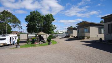 Un parque para caravanas con varias caravanas, un pabellón y un edificio con zona de porche cubierta.