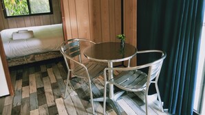 A room with a bed, a round table with two chairs, a small plant on the table, and a window with curtains. - Oval Motel (Murray Bridge)
