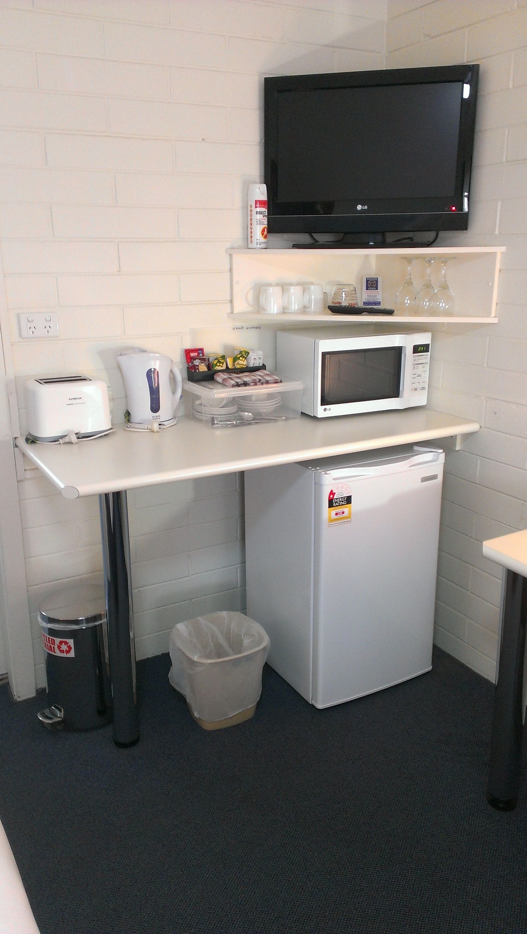 A kitchenette with a microwave, toaster, coffee maker, and a small refrigerator.