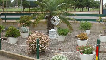 A garden with various potted plants, a windmill, and a fence.