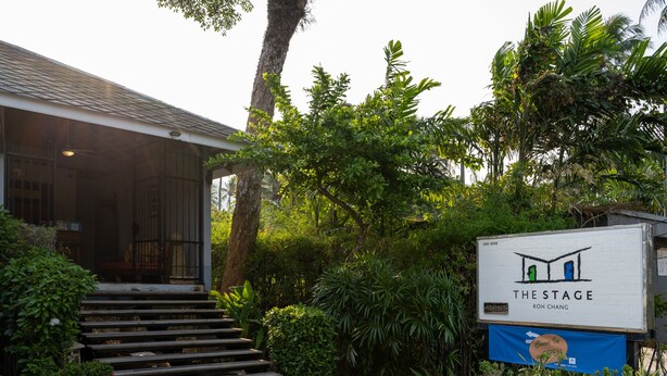Ein Gebäude mit einer Schautafel für 'The Stage Koh Chang' und einer Treppe, die zum Eingang führt.