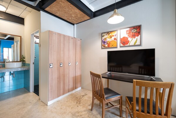Une salle de bain moderne avec un meuble-lavabo en bois, un évier et un miroir. On aperçoit une zone de douche à l’arrière-plan.
