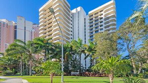 Un hotel moderno con varios balcones, rodeado de exuberante vegetación y palmeras.