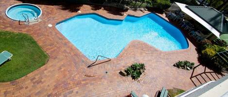Piscina com deck de tijolos, uma piscina pequena circular e uma cadeira de descanso.