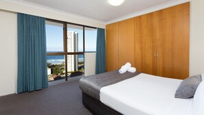 Habitación de hotel con una cama grande, un armario y vistas al océano.