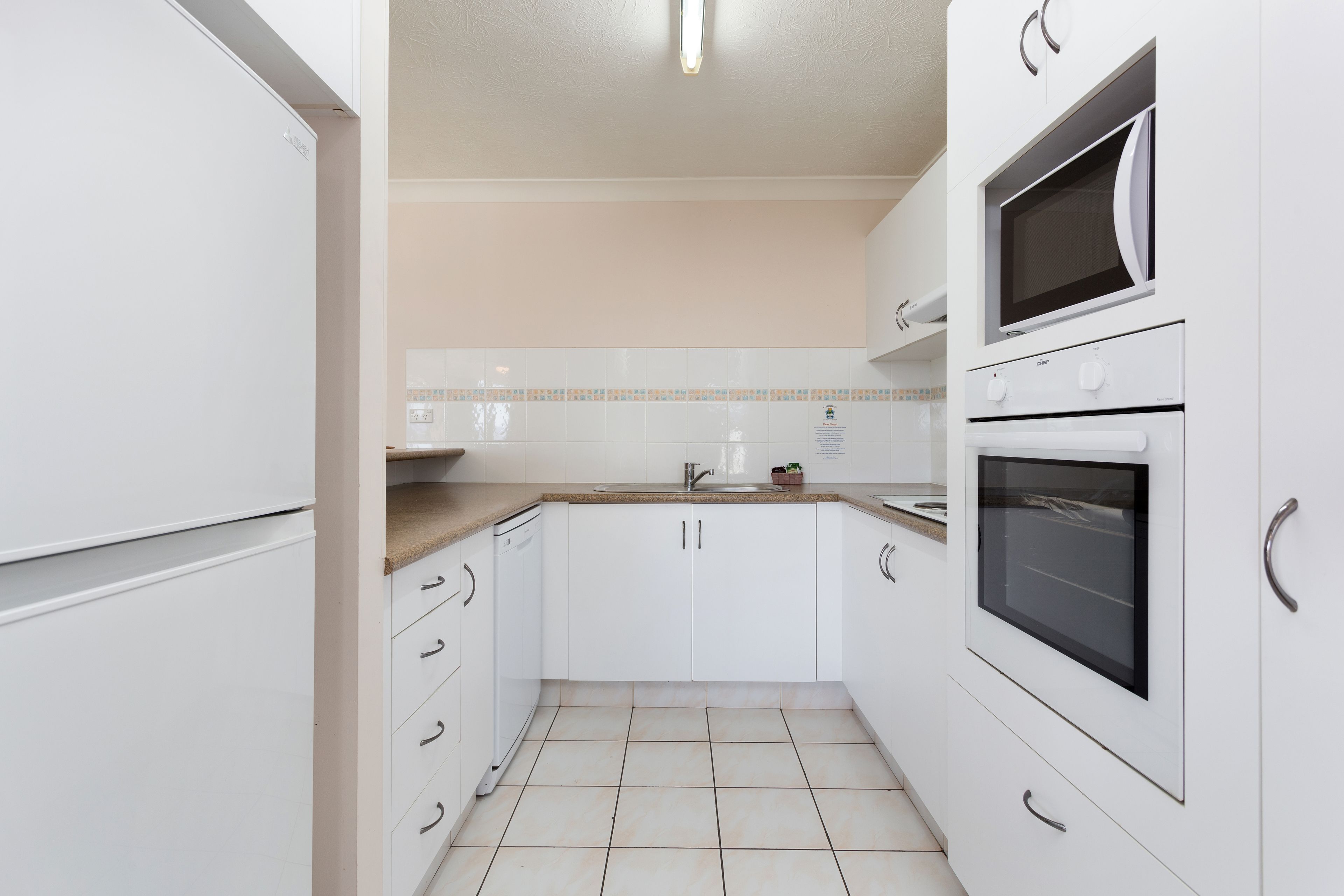 A compact kitchen with white cabinets, a microwave, and a sink.