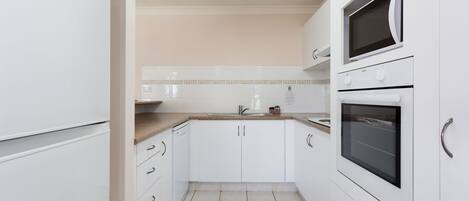 A compact kitchen with white cabinets, a microwave, and a sink.
