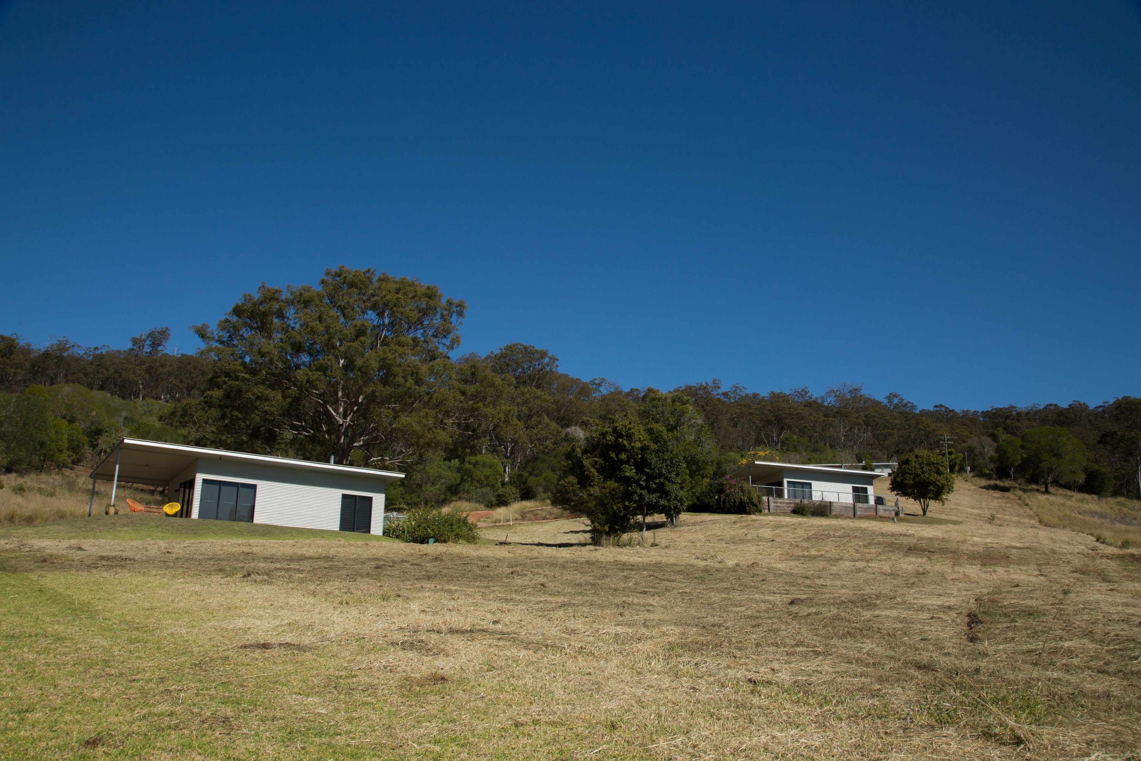 A rural property with two small buildings, one with a garage and the other with a covered porch.