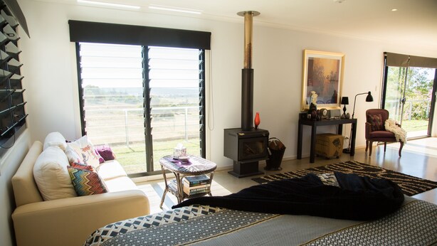 Una sala de estar moderna con un sofá, un tapiz estampado, una chimenea y vistas amplias a través de grandes ventanales.