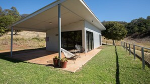 Una casa moderna con un porche cubierto, una silla y plantas en macetas.