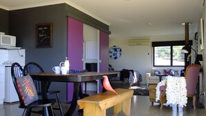Una sala de estar moderna con comedor, una cocina con microondas y un amplio ventanal que proporciona luz natural.