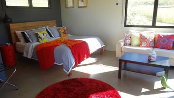 A bedroom with a bed, a sofa, a coffee table, and a red rug.