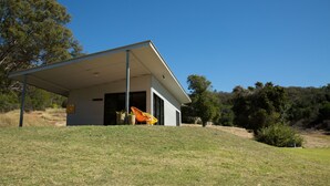 Una casa moderna con un porche cubierto, una puerta y un pequeño jardín.