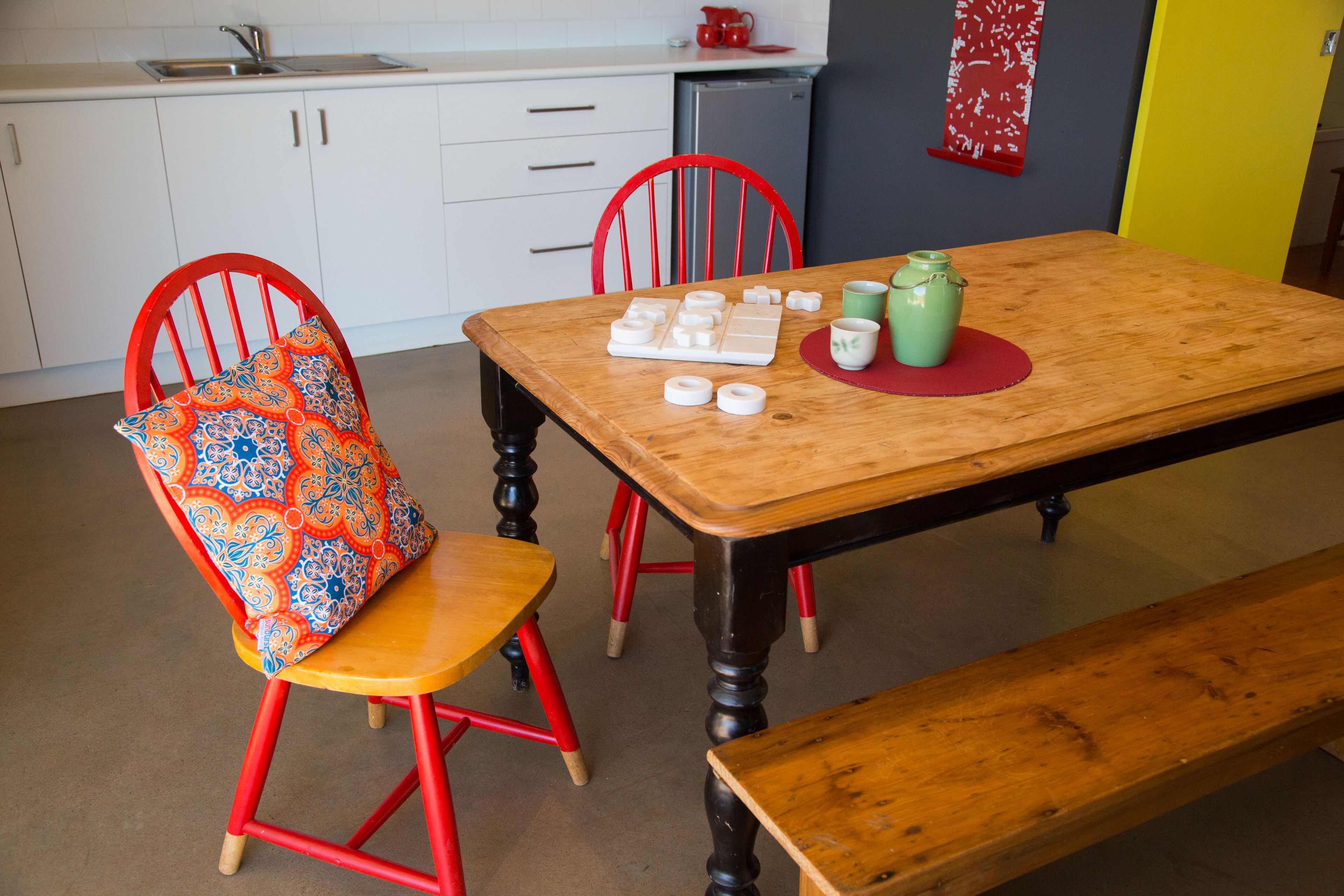 A dining area with a wooden table, red chairs, and a bench.
