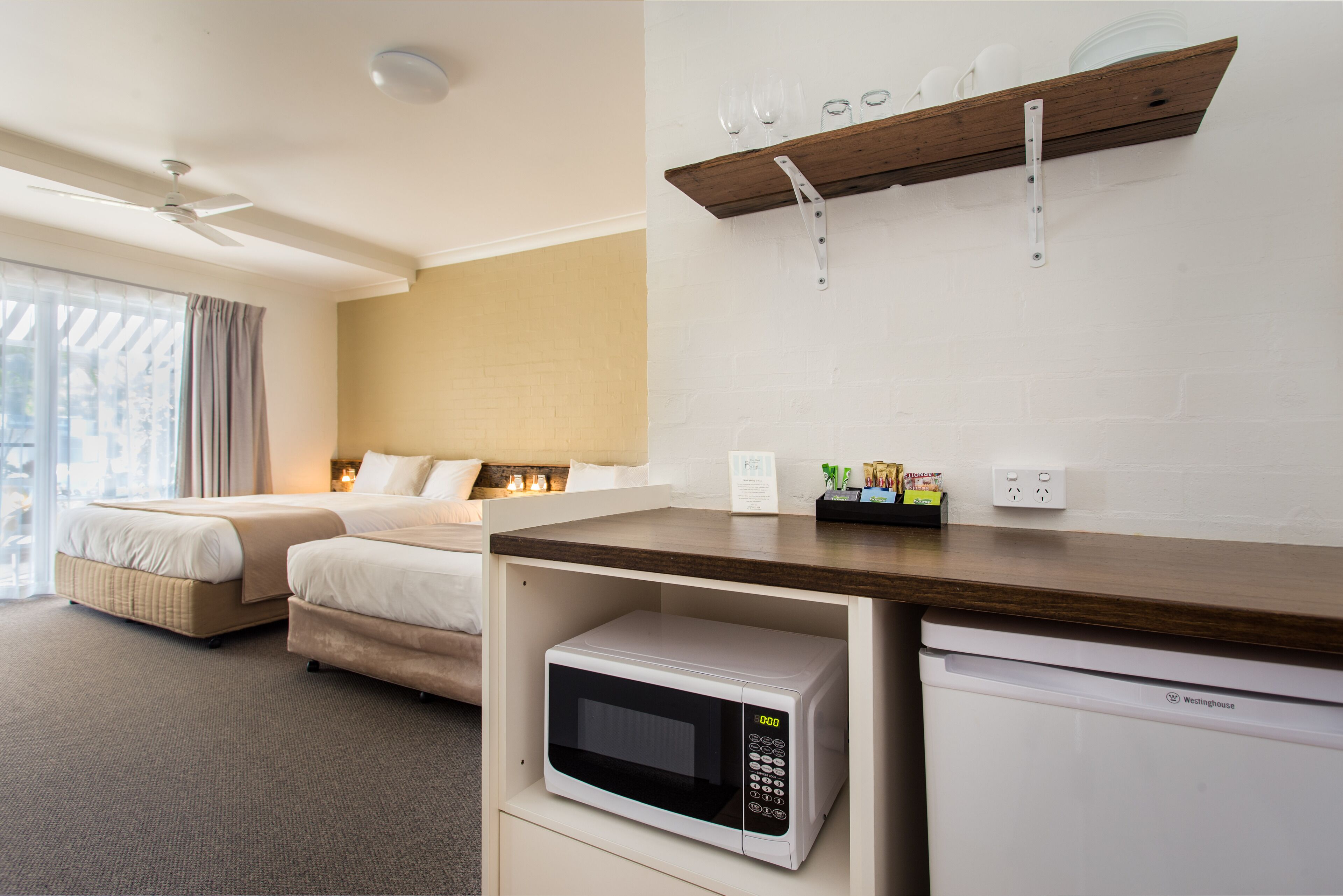 Ein Hotelzimmer mit einem Bett, einer Mikrowelle, einem Geschirrspüler und einem Regal mit Gläsern.