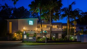 Un motel con un cartel que indica habitaciones disponibles, una entrada bien iluminada y un área de estacionamiento.